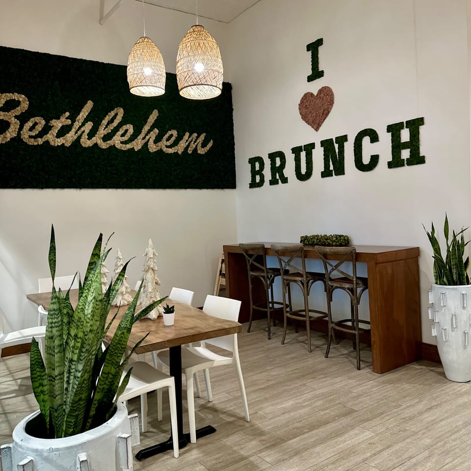 Cafe Crewy's dining area with "Bethlehem" and "I love Brunch" moss wall art, tables, and bar seating.